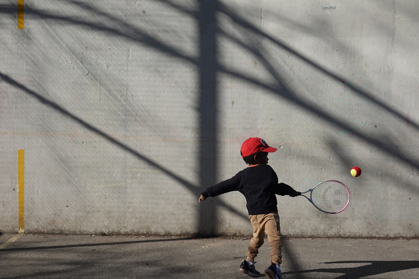 Young child practicing tennis with a junior racket and beginner ball